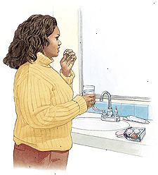 Donna in piedi al lavandino del bagno prendendo pillola anticoncezionale.