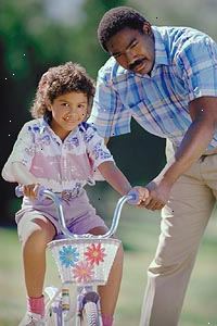 Immagine di un padre che insegna alla figlia di andare in bicicletta