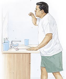L'uomo in piedi nel lavandino lavarsi i denti con la schiena dritta, piegando leggermente sui fianchi.
