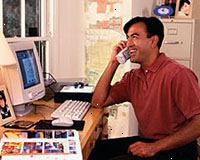 Immagine di un uomo che lavora al computer, parlando al telefono